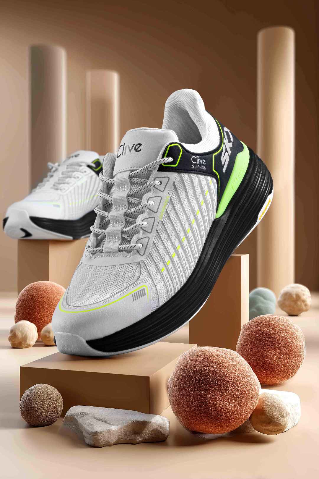 White and black athletic shoes with green accents on a geometric platform with decorative stones and spheres.