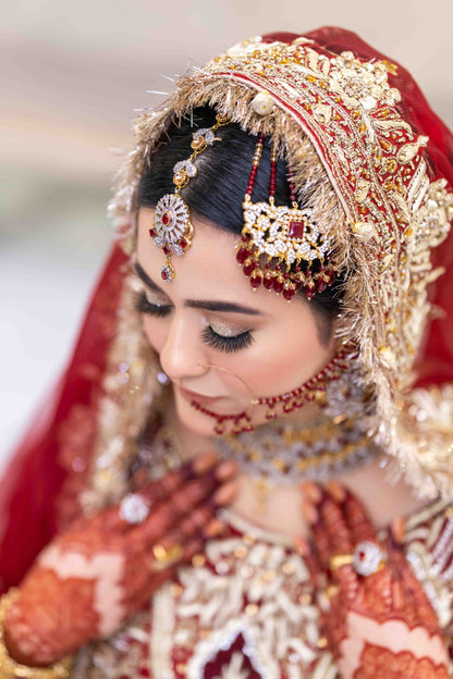Bride wearing traditional jewelry and a red veil with a blurred background