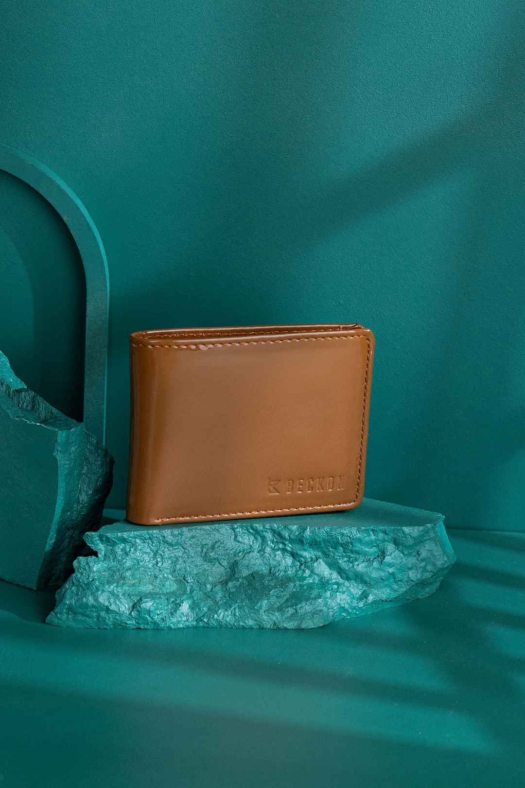 creative studio shot of brown leather wallet on placed on stone surface teal background
