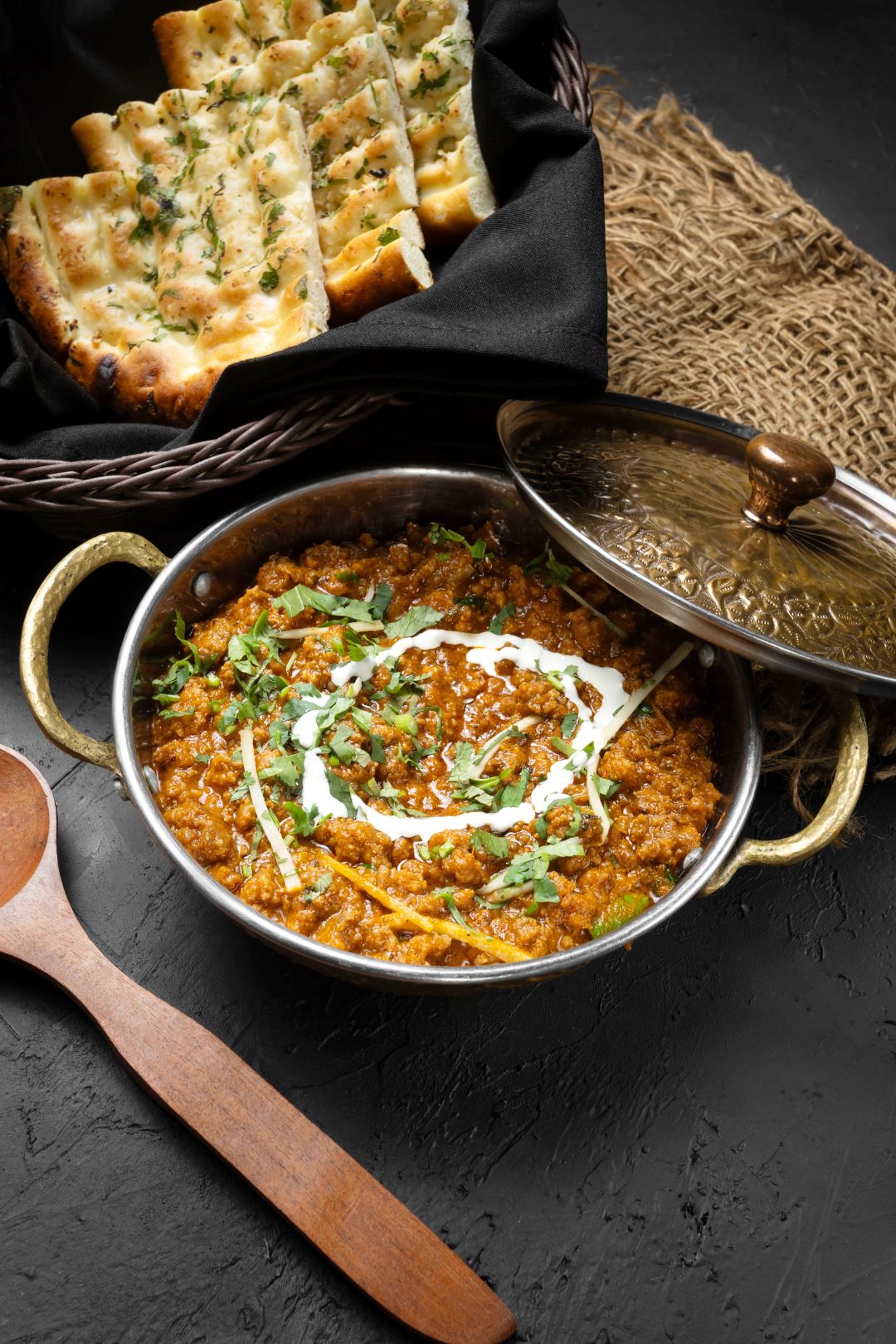 creative restaurant food photography of dum keema with naan bread on a dark surface